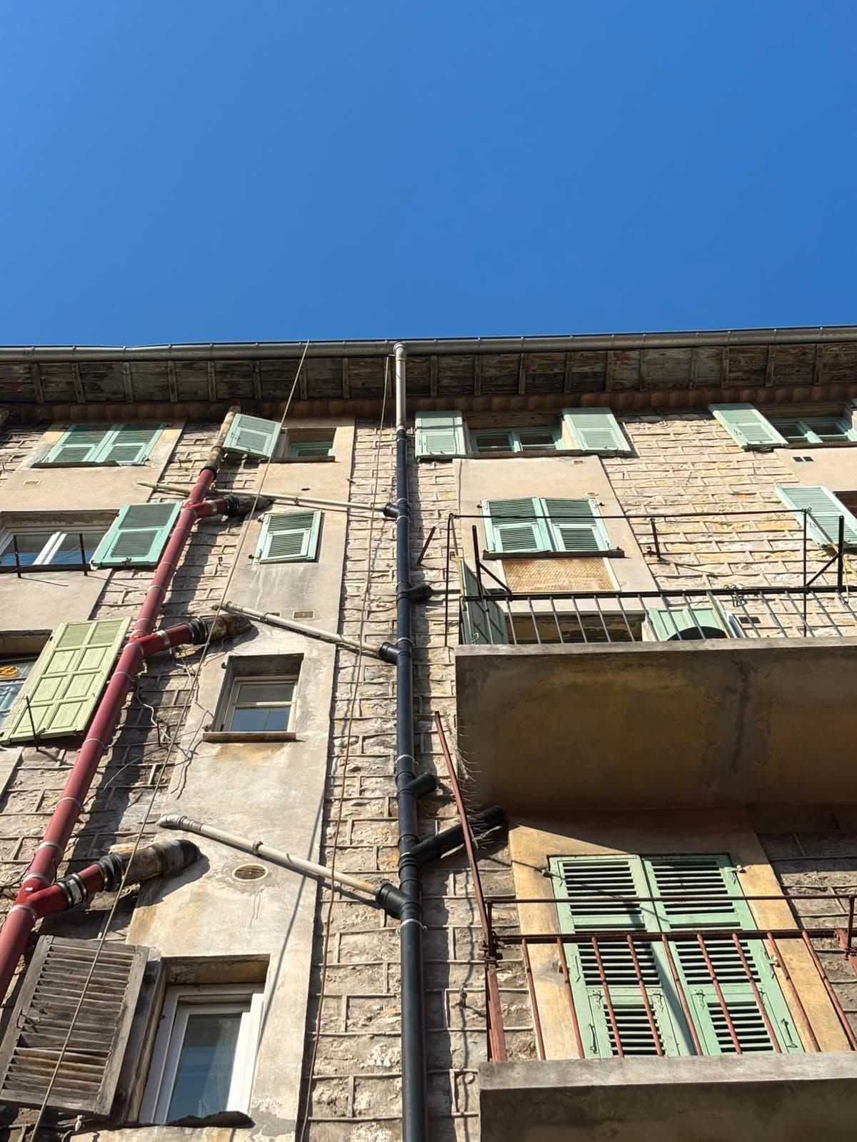 Colonnes d'évacuation neuves posées sur la façade d'un immeuble ancien à Nice